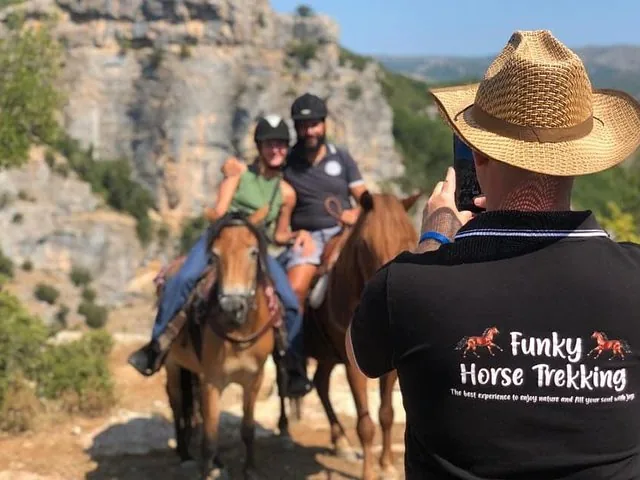 Une personne prenant en photo deux personnes à cheval dans un paysage rocheux.