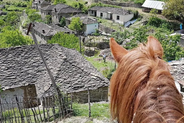 Veduta di un villaggio in pietra dalla prospettiva di una persona a cavallo.