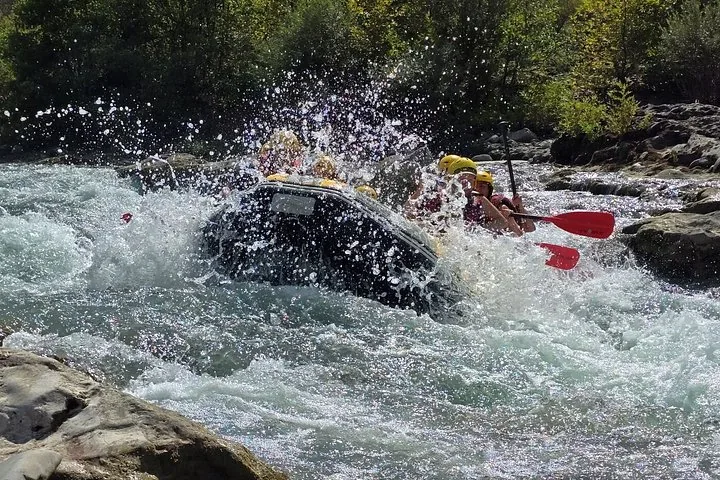 People in a raft getting heavily splashed by a large wave during whitewater rafting.