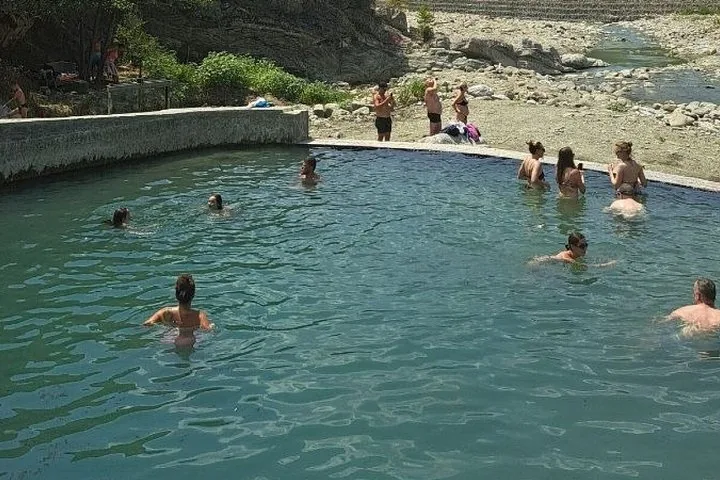 Persone che nuotano e si rilassano in una piscina artificiale accanto a un fiume.